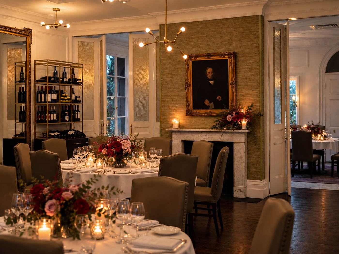 Henry's Table by candlelight, round tables dressed with roses beneath the portrait of Sir Henry Ayers