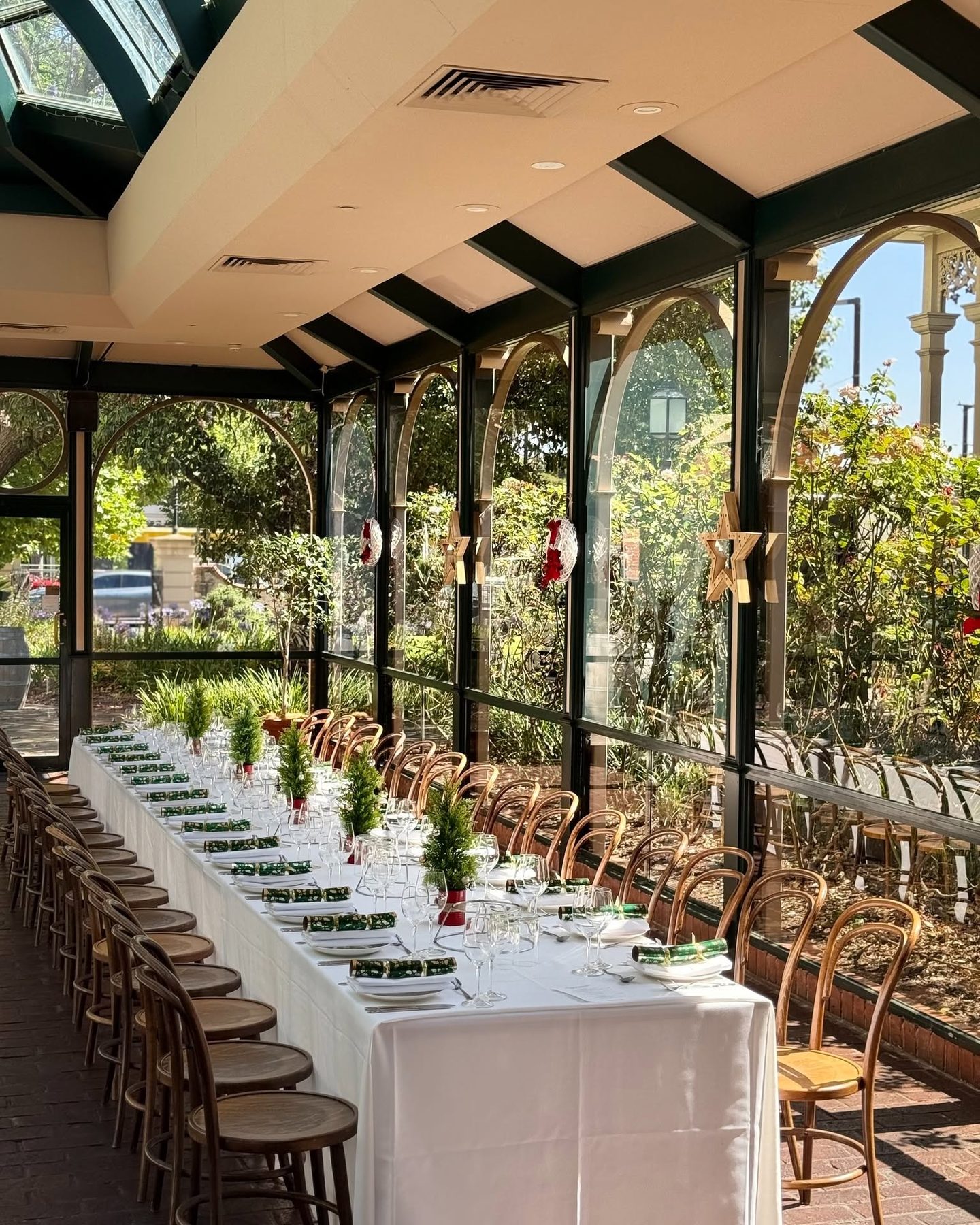 A Christmas long table in the Conservatory, with small trees and crackers down its length
